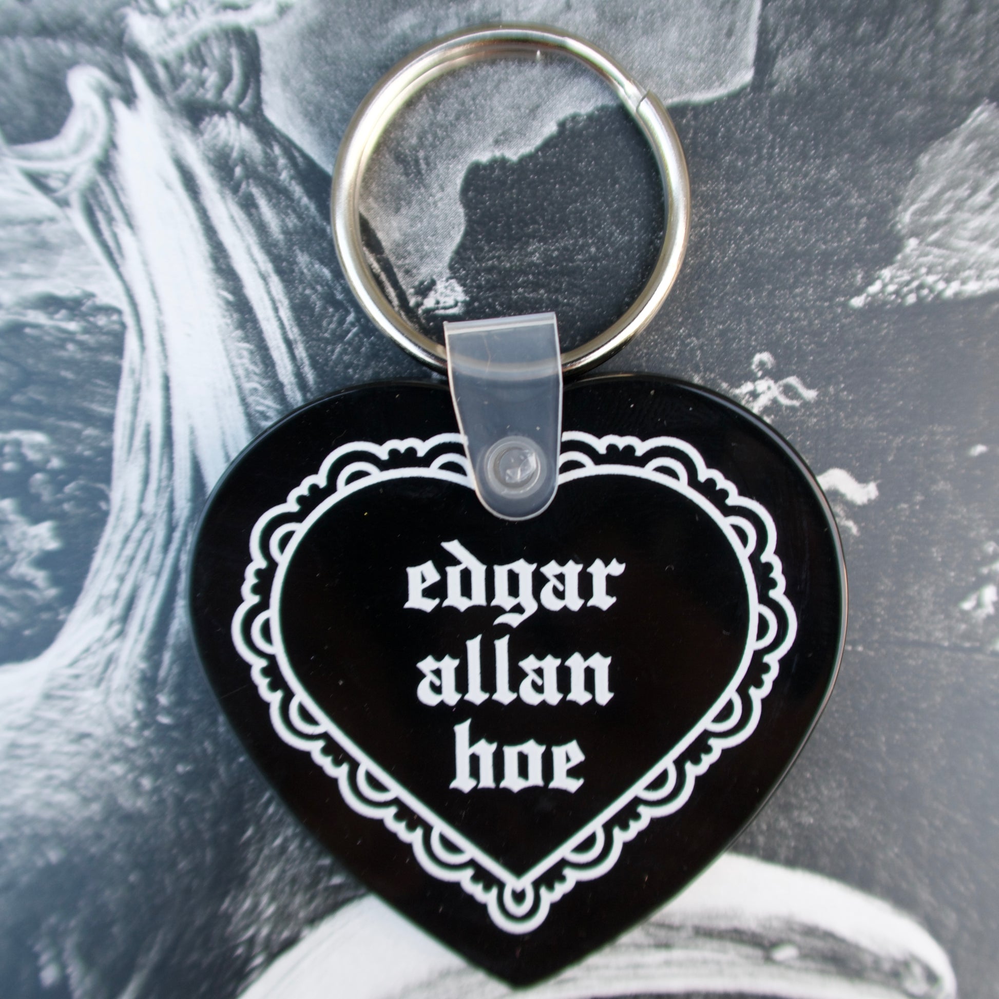 Heart-shaped keychain with 'edgar allan hoe' text on a black background