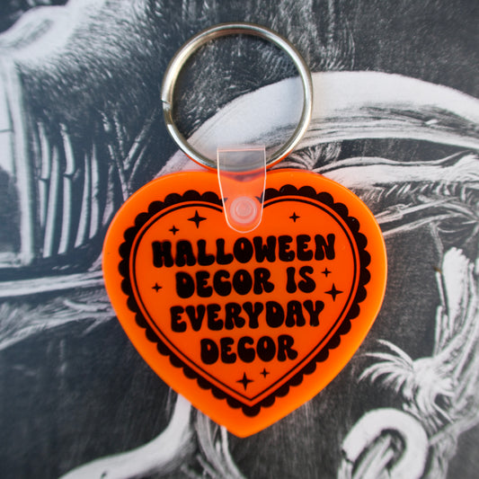 Heart-shaped keychain with 'Halloween decor is everyday decor' text on an orange background.